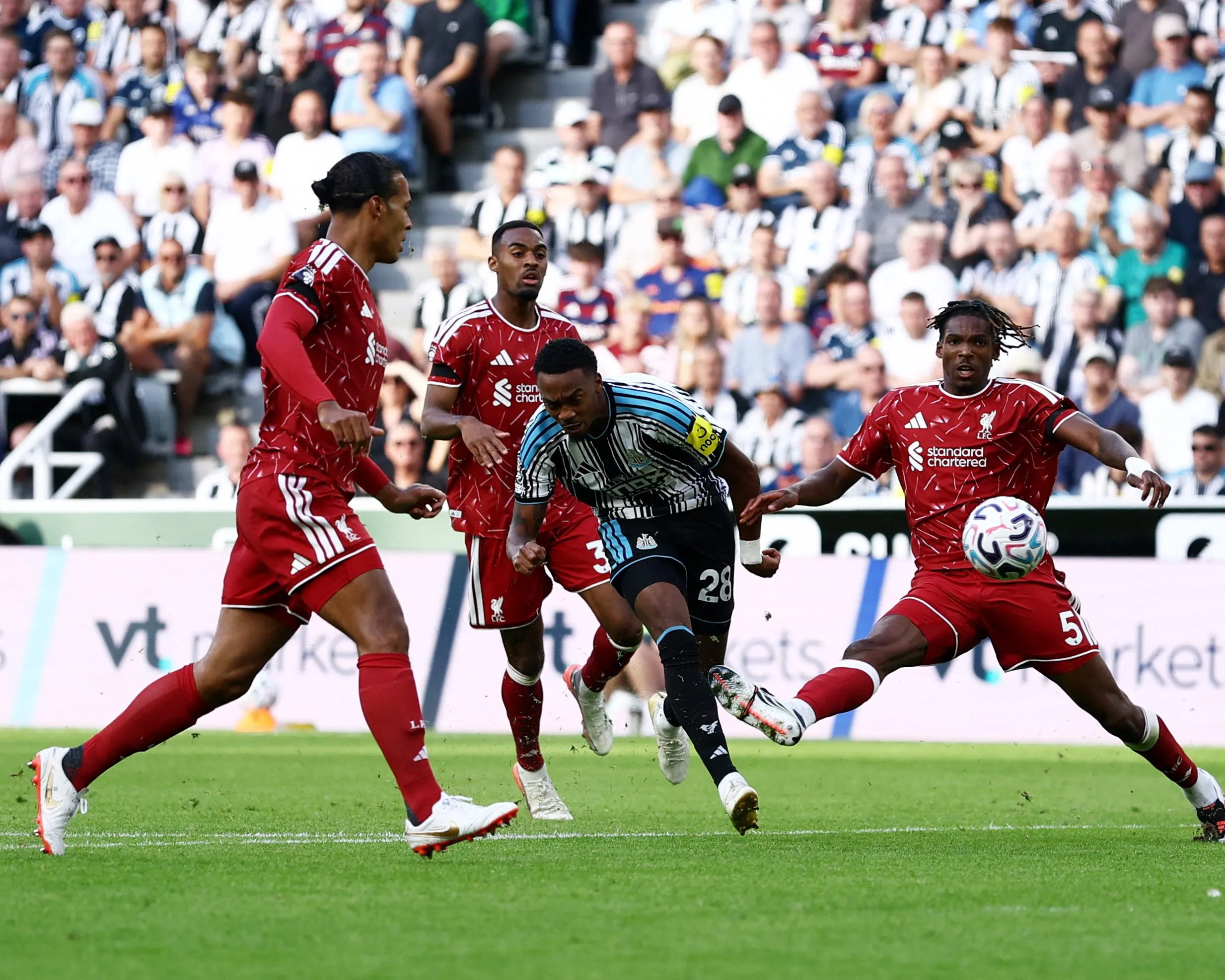 Joe Willock scores a goal despite the attentions of several Liverpool players