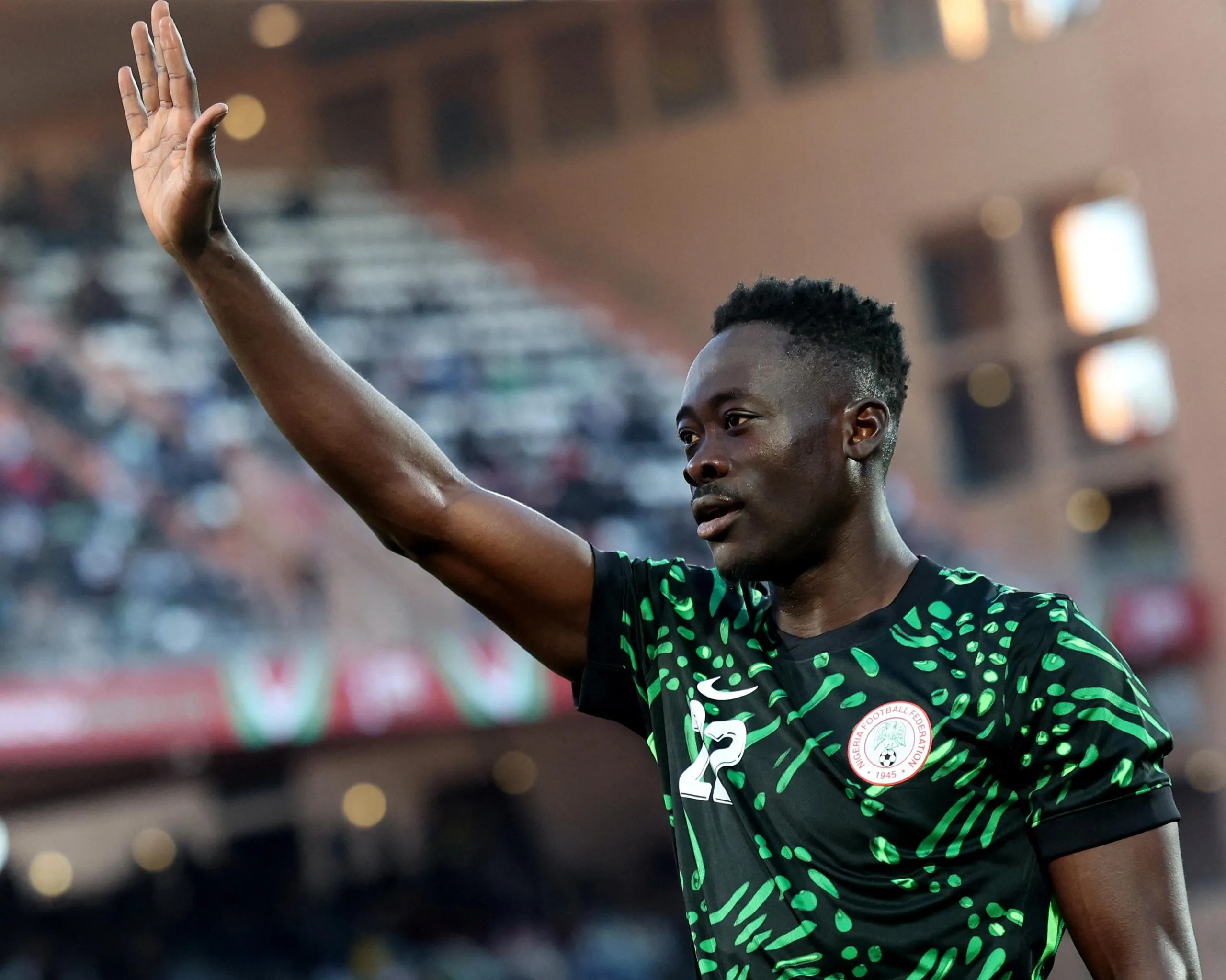 Akor Adams holding his hand up in the air with crowds in the stadium behind him