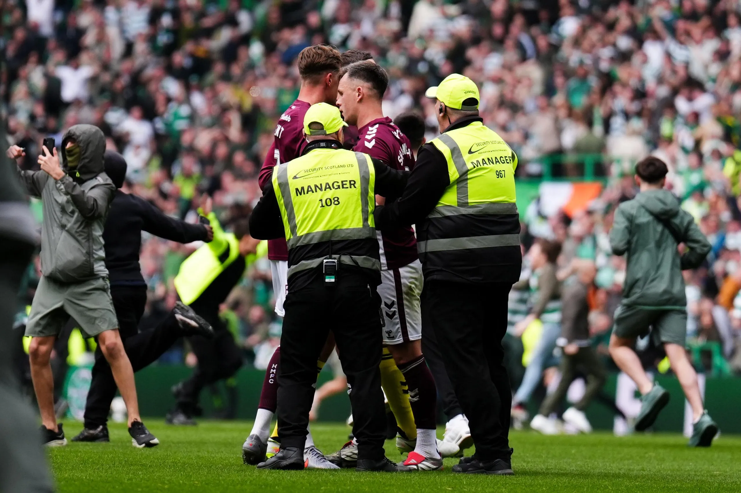 Lawrence Shankland is escorted from the Celtic Park pitch by security
