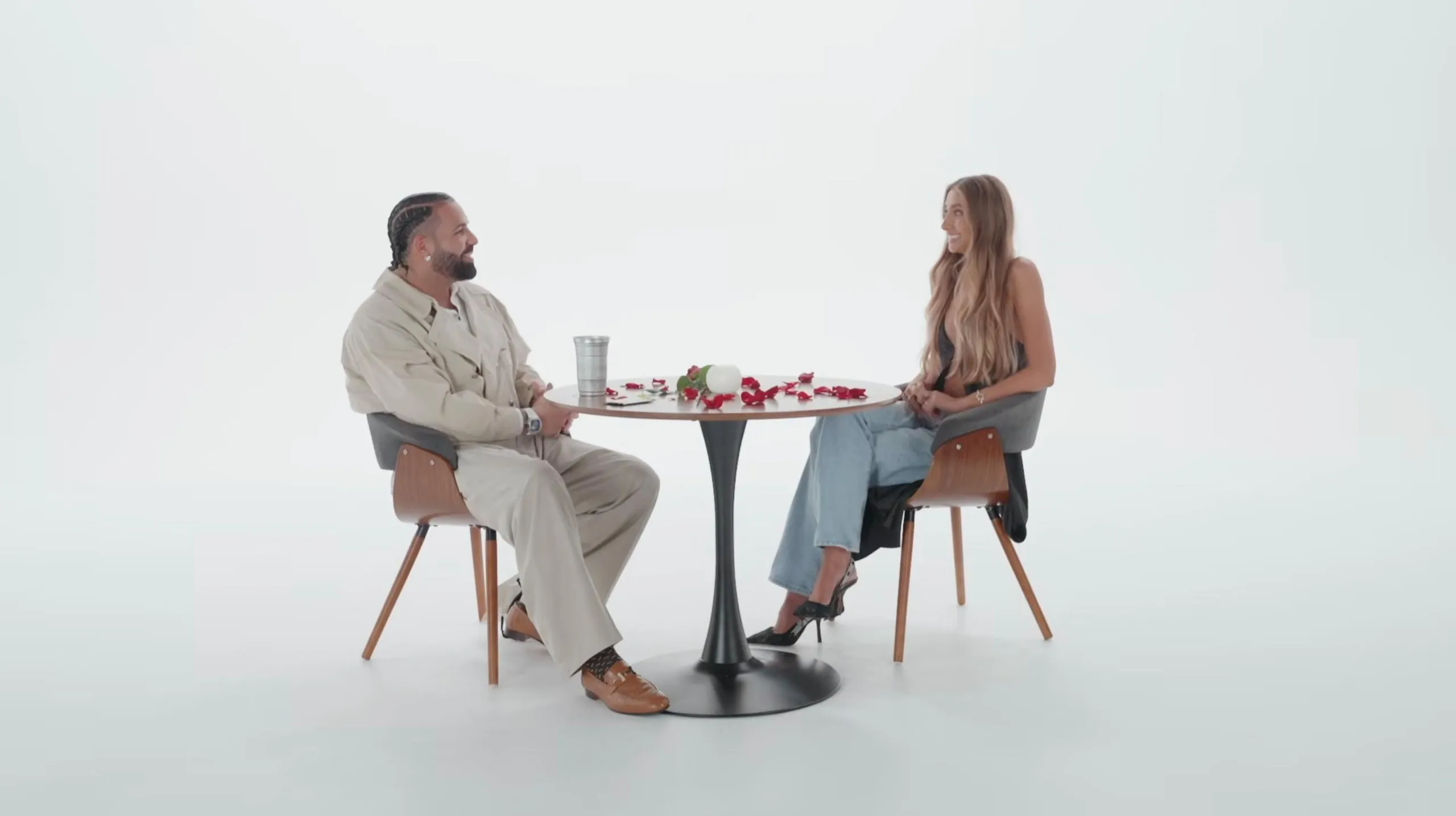 A man and woman sitting at a table in a white room 