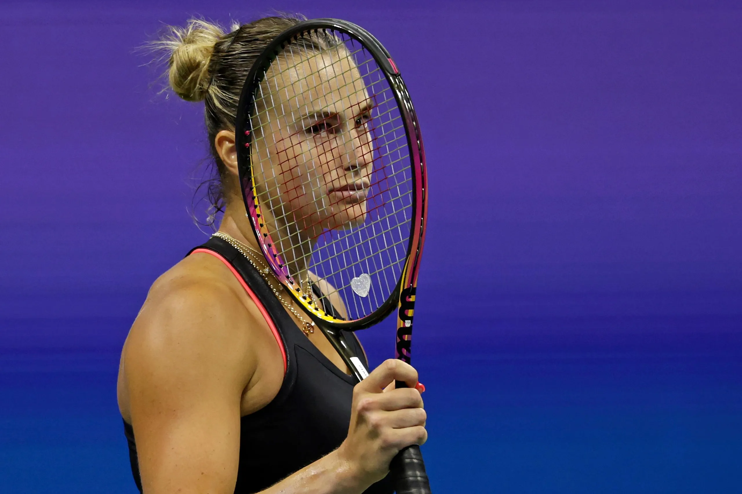 Aryna Sabalenka looks dejected behind her racket on court