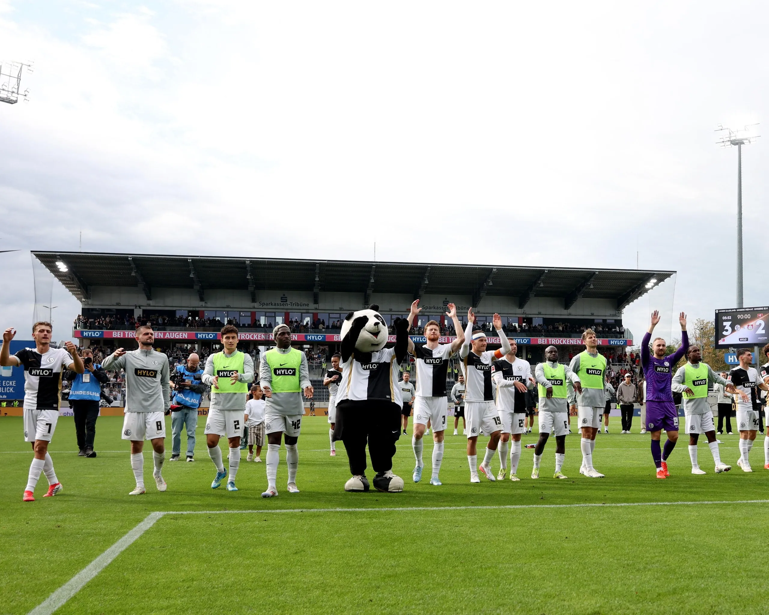 Elversberg players – and mascot – celebrate in front of their home fans after the 3-2 win against Leverkusen.