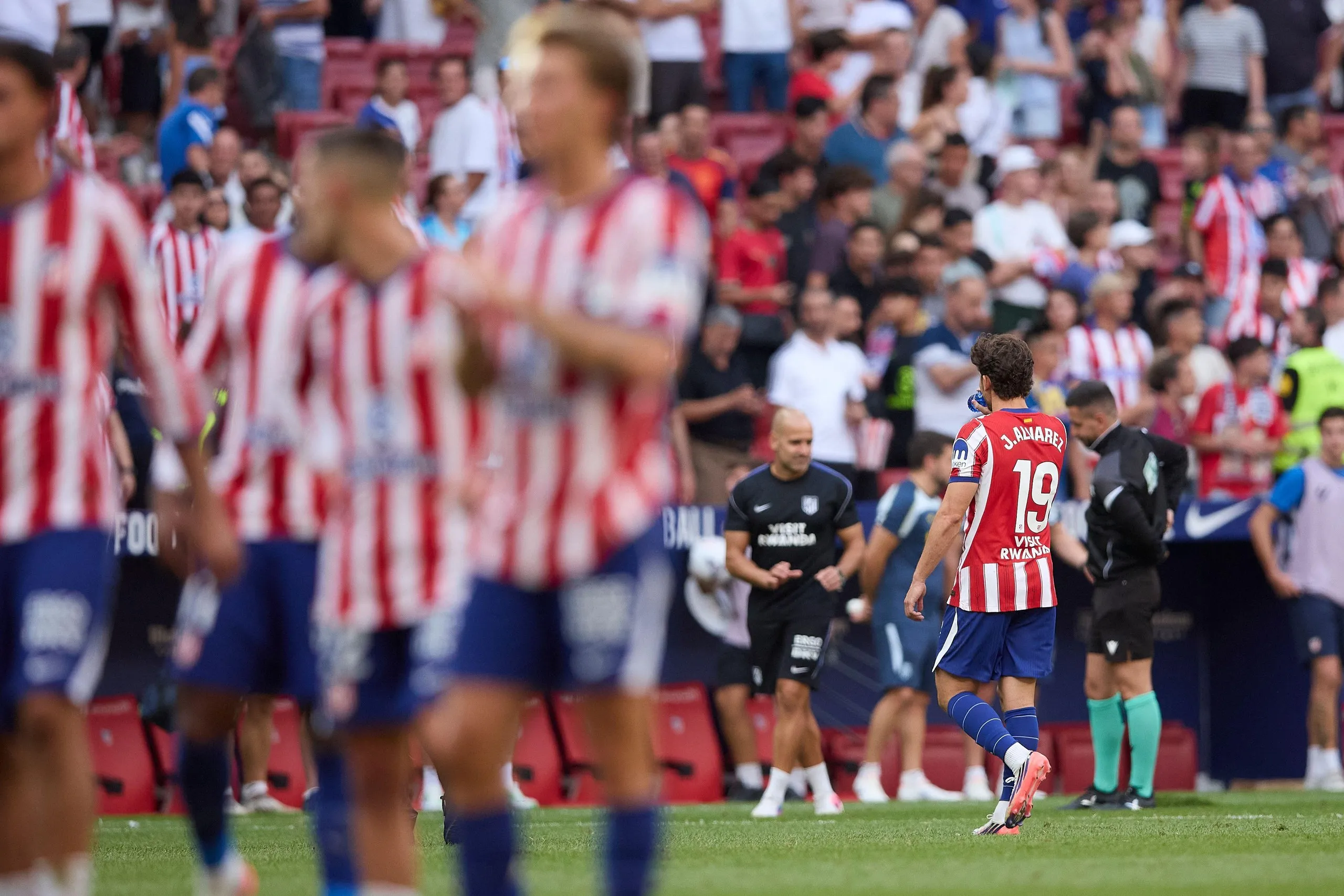 Julián Alvarez trudges off the pitch alone as his Atlético Madrid teammates applaud the fans.