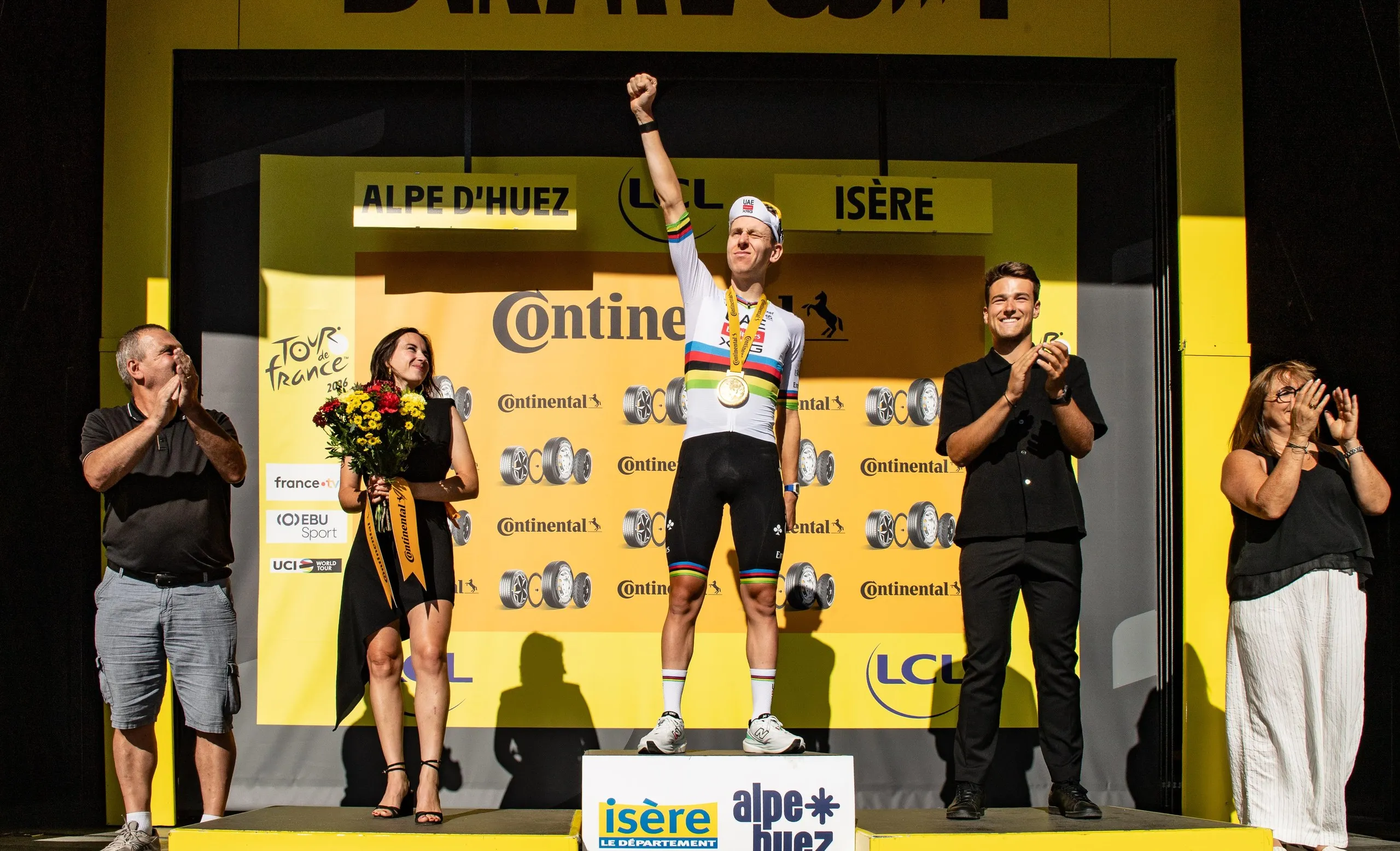 Tadej Pogacar celebrates on the podium after winning stage 19.