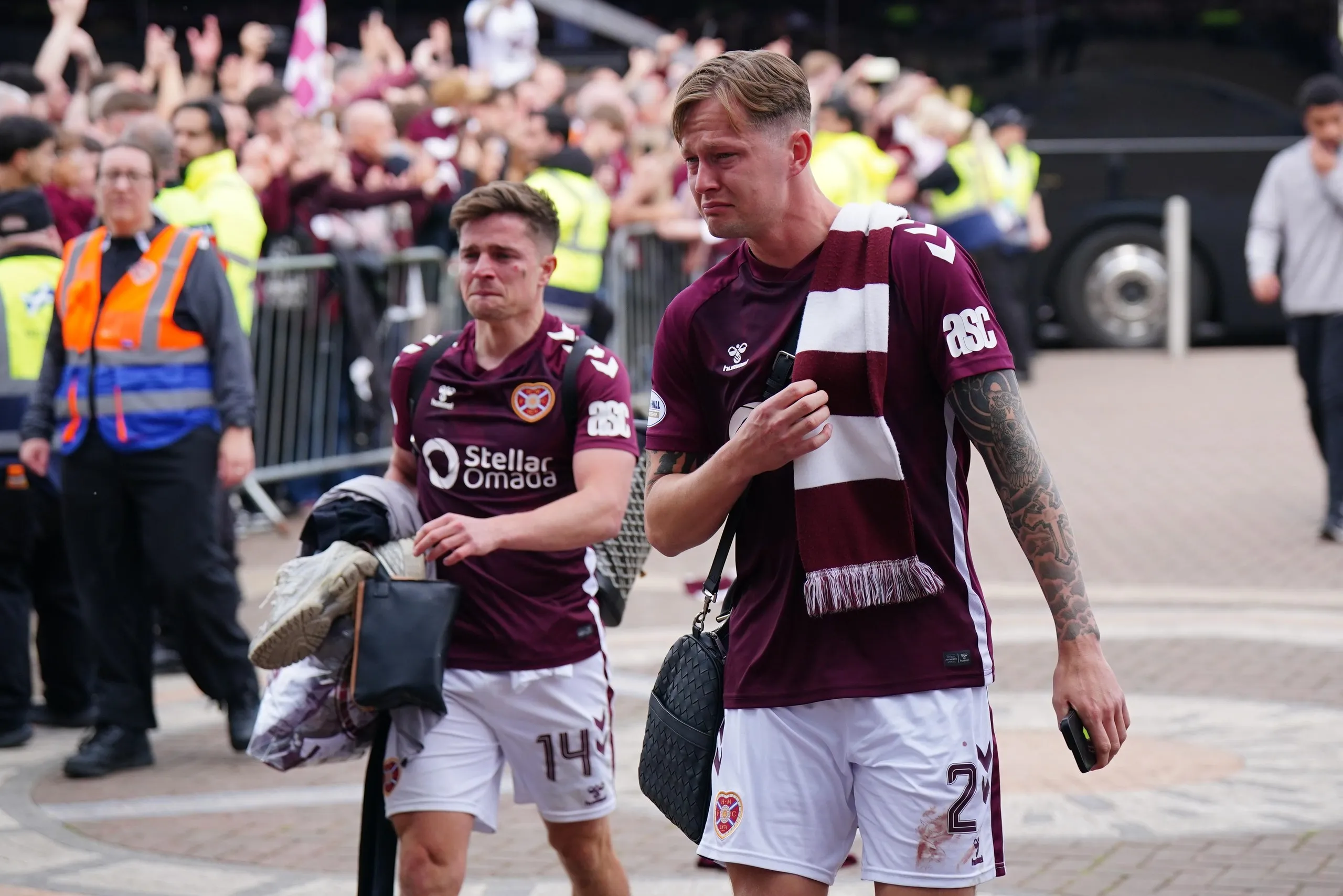 Hearts players Cameron Devlin and Frankie Kent walk past fans as they arrive at Tynecastle Park after the match.