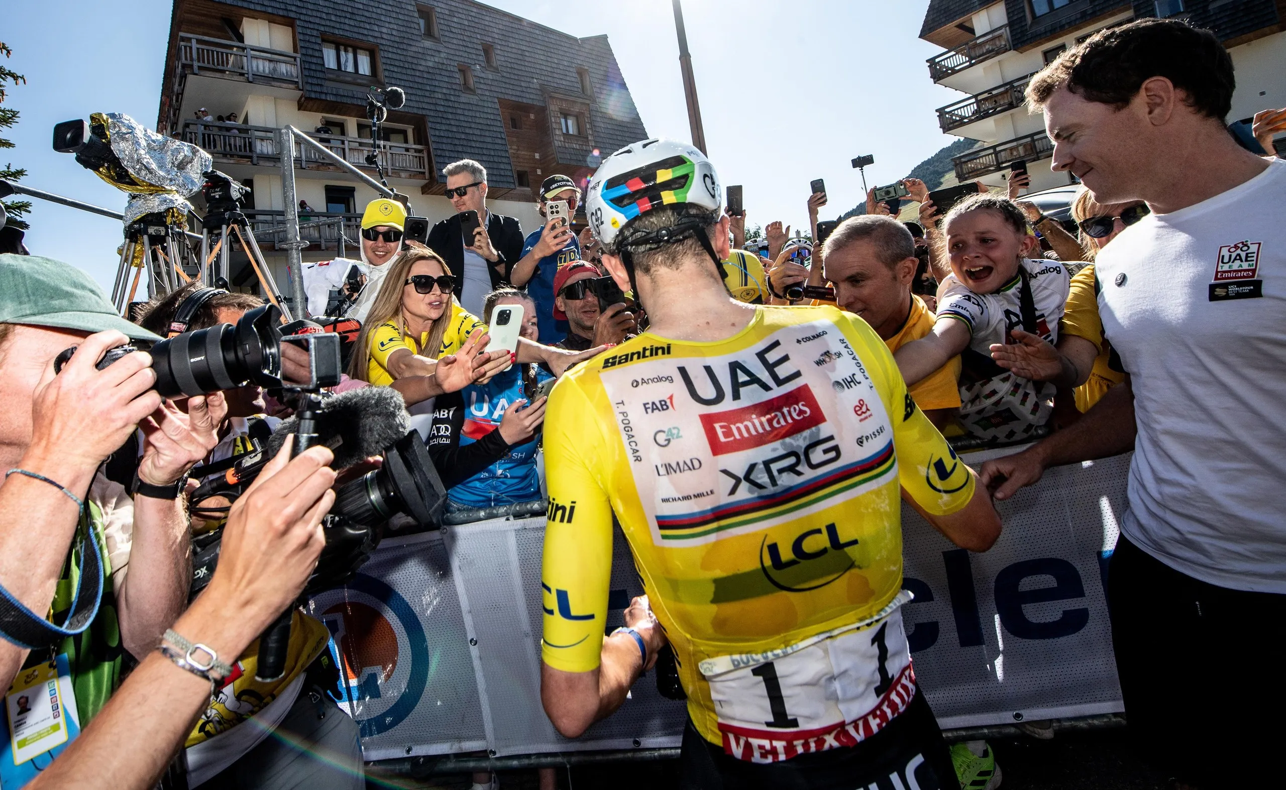 Tadej Pogacar celebrates with fans after crossing the finish line to win stage 19.