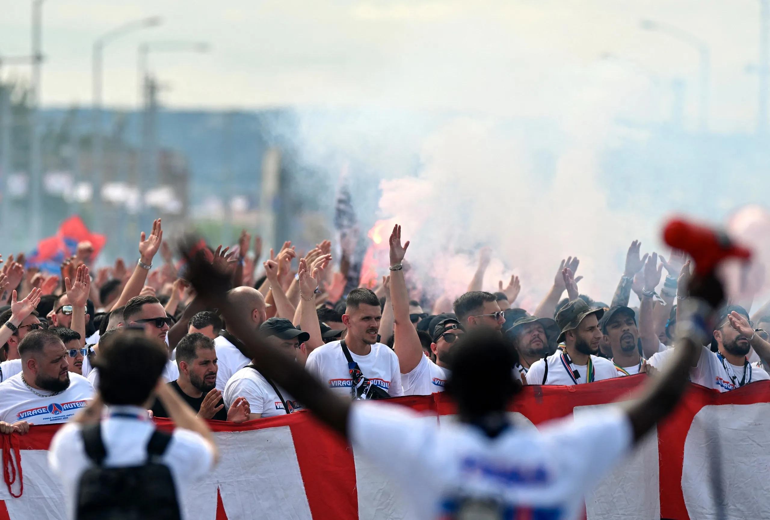 PSG supporters cheer and light flares.