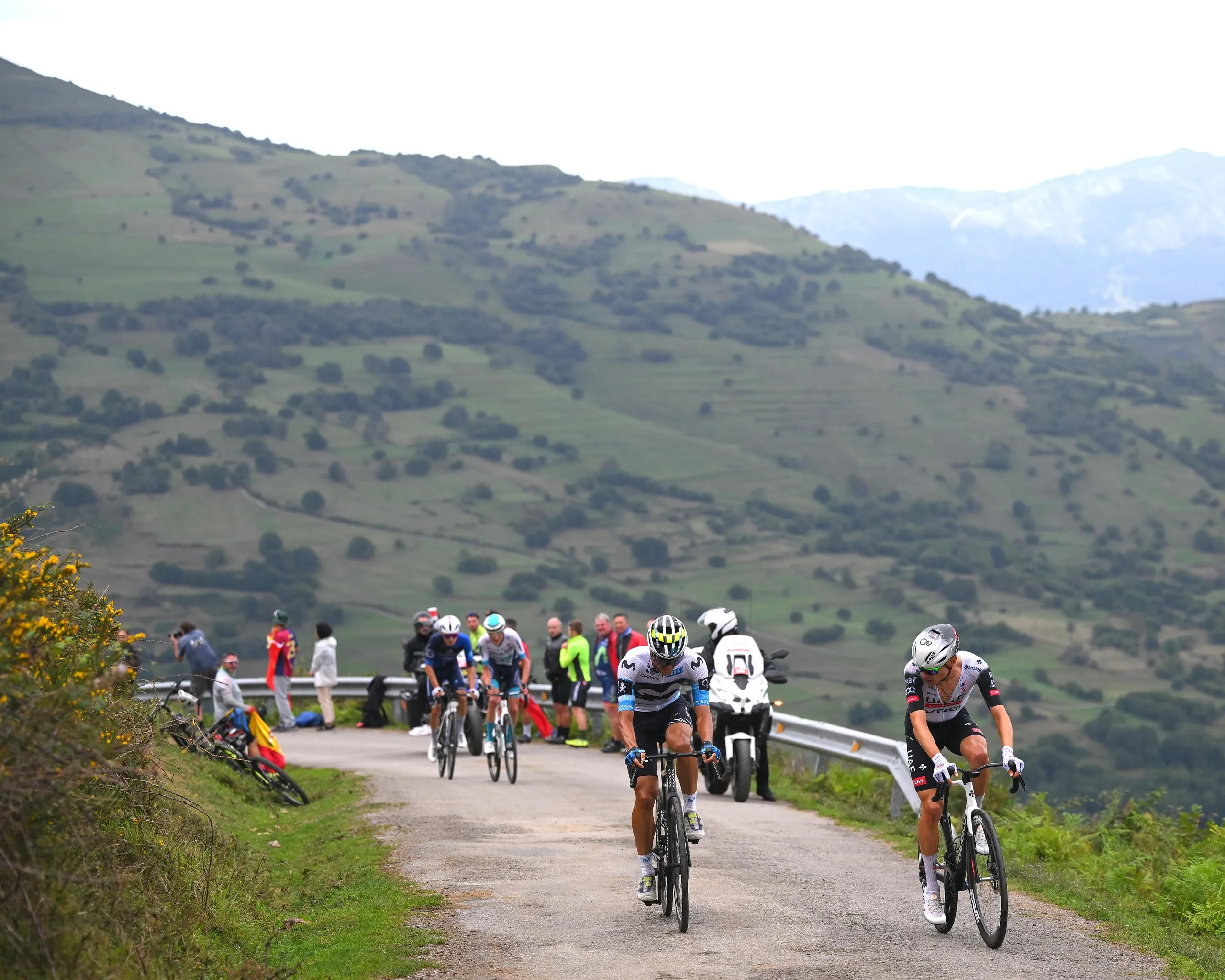 Javier Romo and Juan Ayuso cycling against a hilly backdrop