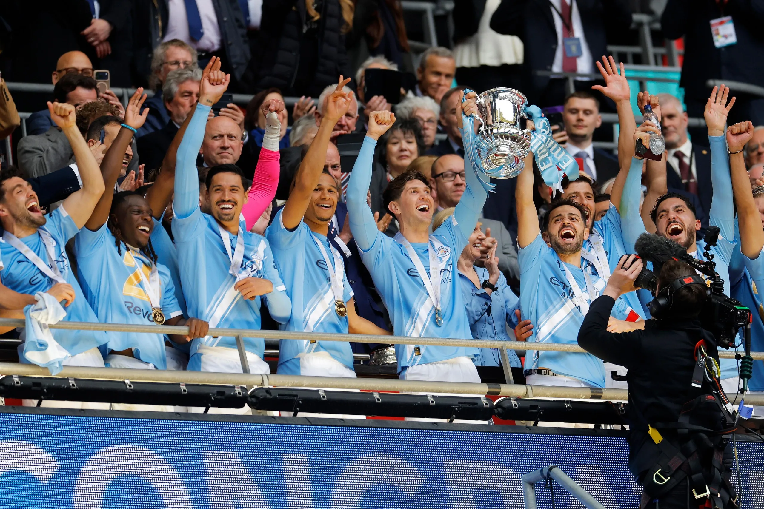 John Stones and Bernardo Silva of Manchester City lift the FA Cup trophy.