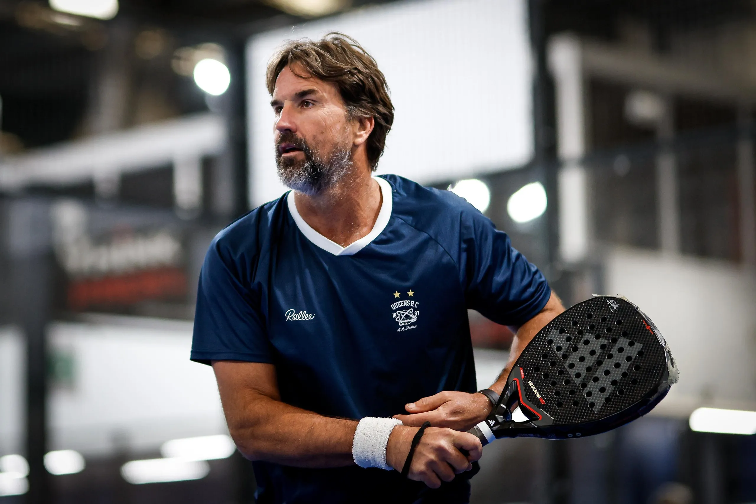 An action shot of Pat Rafter holding a padel racket