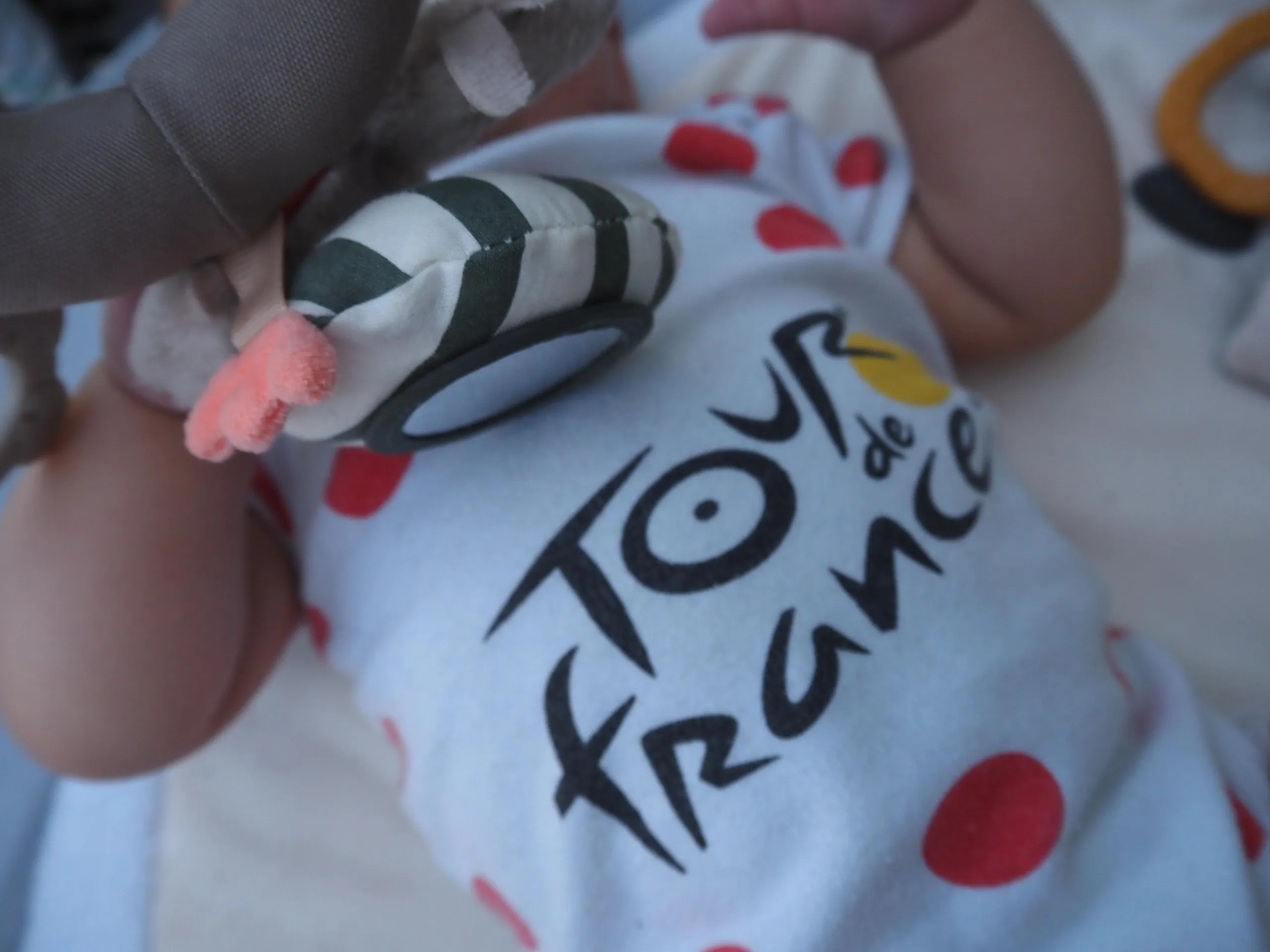 A baby sporting a red polkadot babygrow.