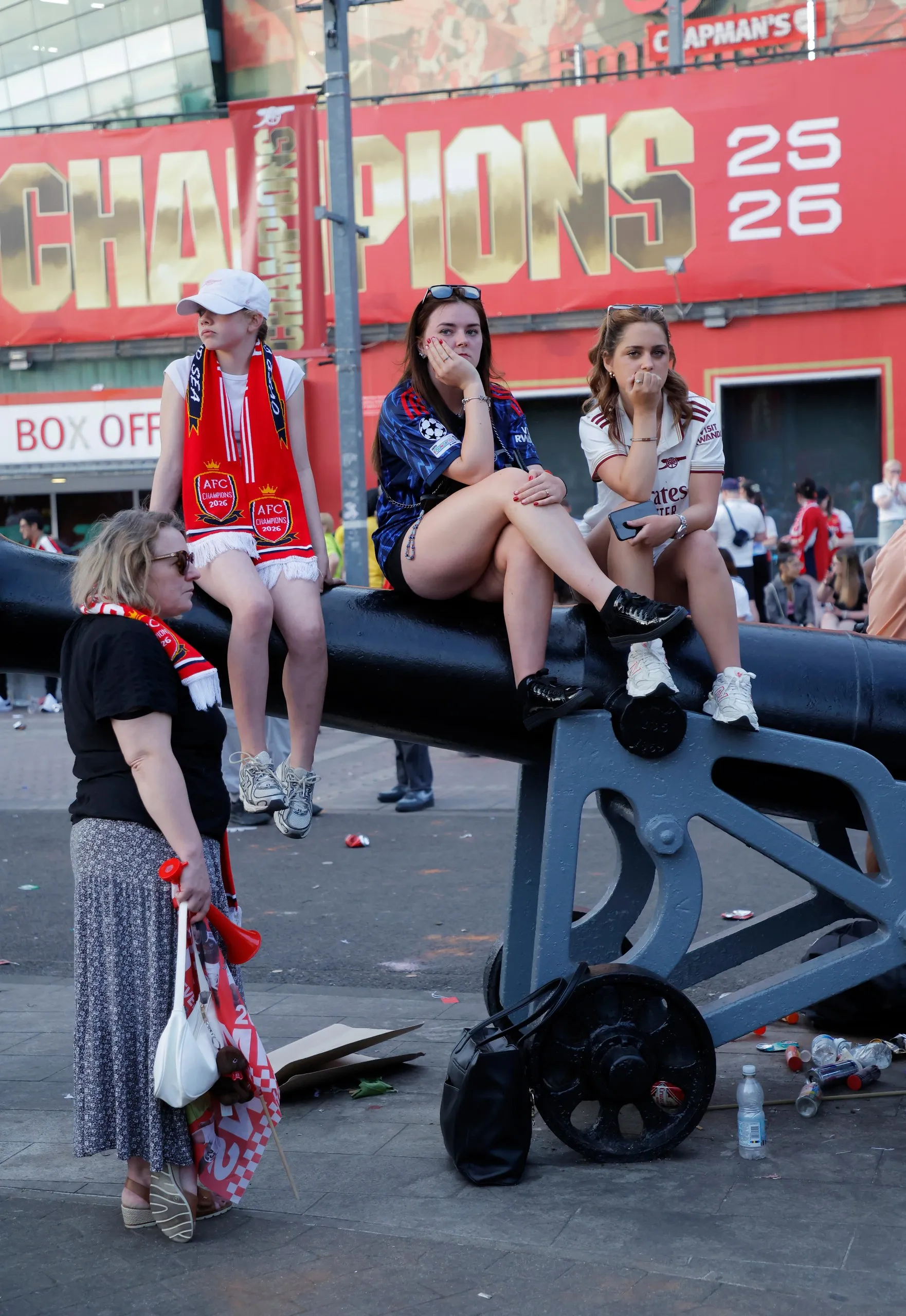 Arsenal fans dejected sitting on one of the cannons outside the Emirates Stadium after the defeat in the Champions League final.