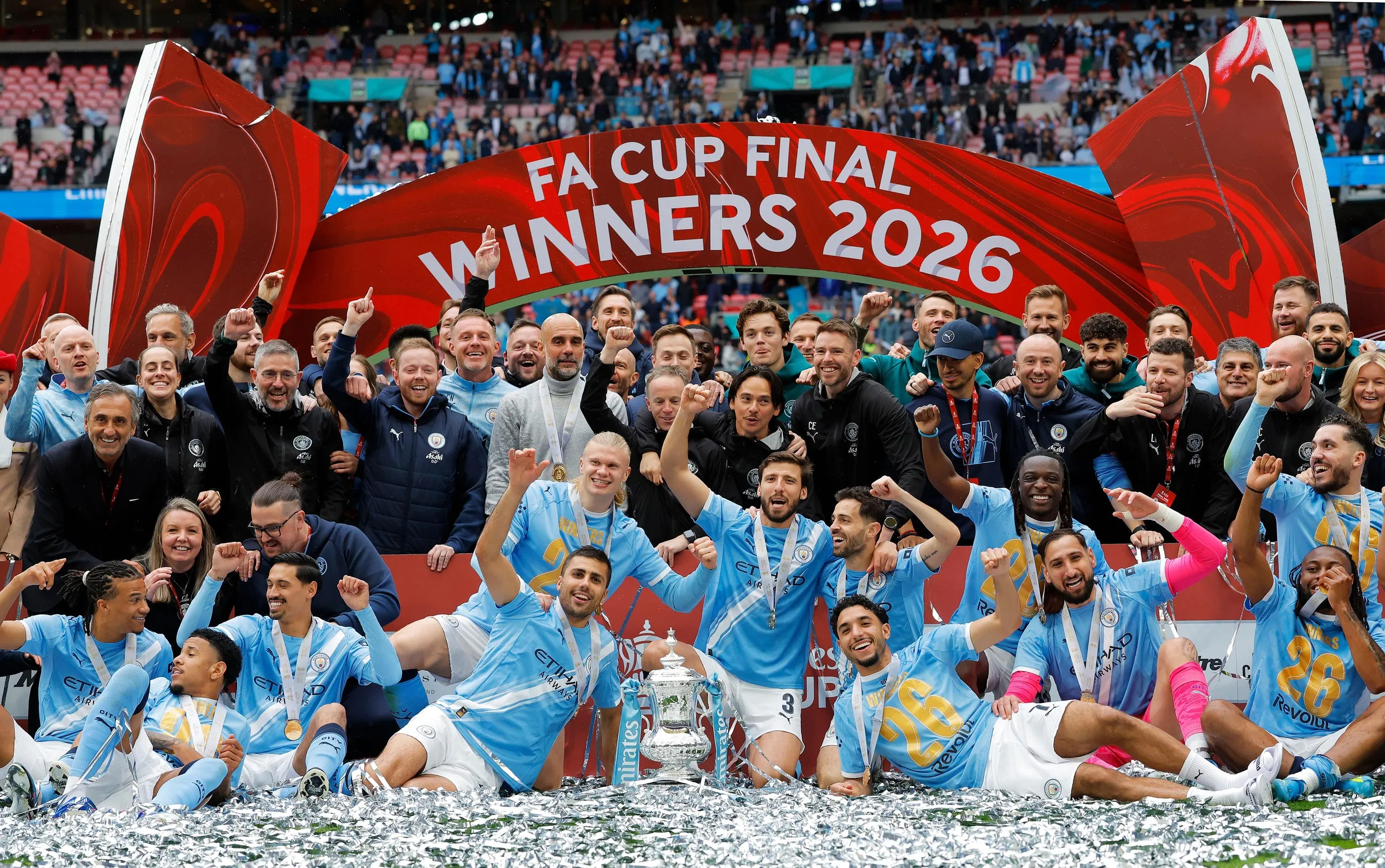 Manchester City players and staff celebrate with the FA Cup trophy.
