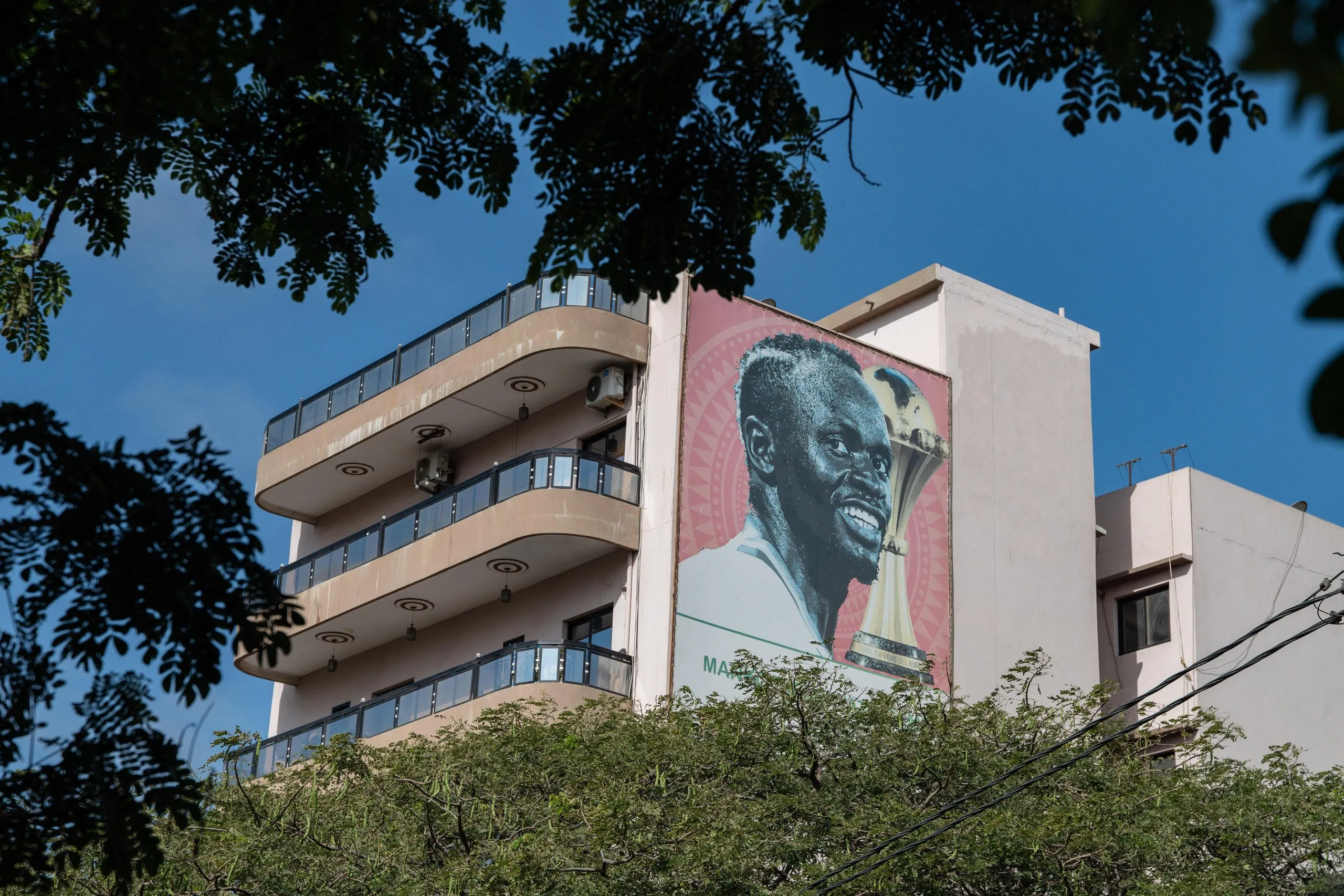 A large poster of Senegal’s captain Sadio Mané alongside the 2025 Afcon trophy on a residential building in Dakar