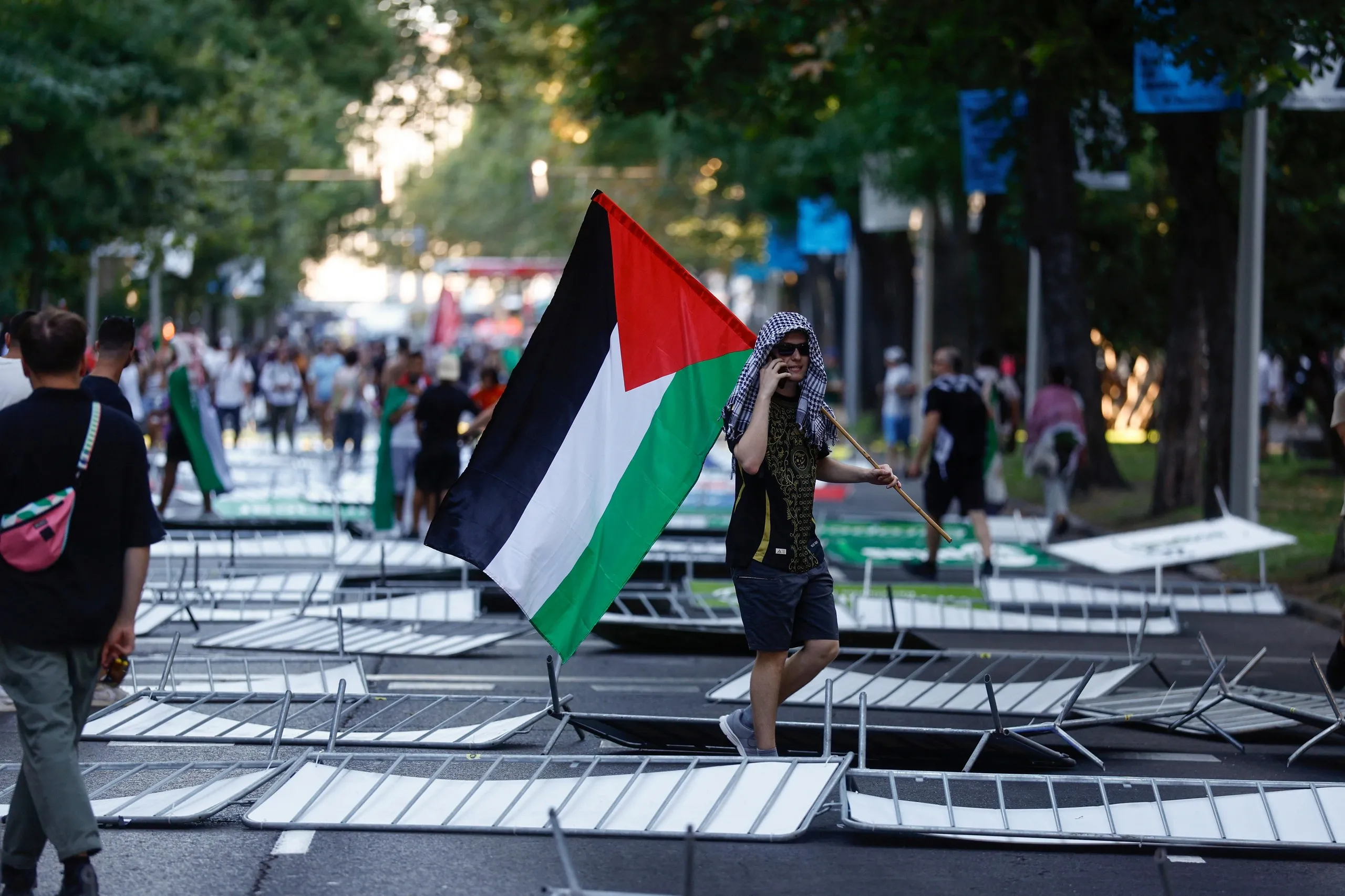 Demonstrators, some holding Palestinian flags, stand among knocked-down barricades