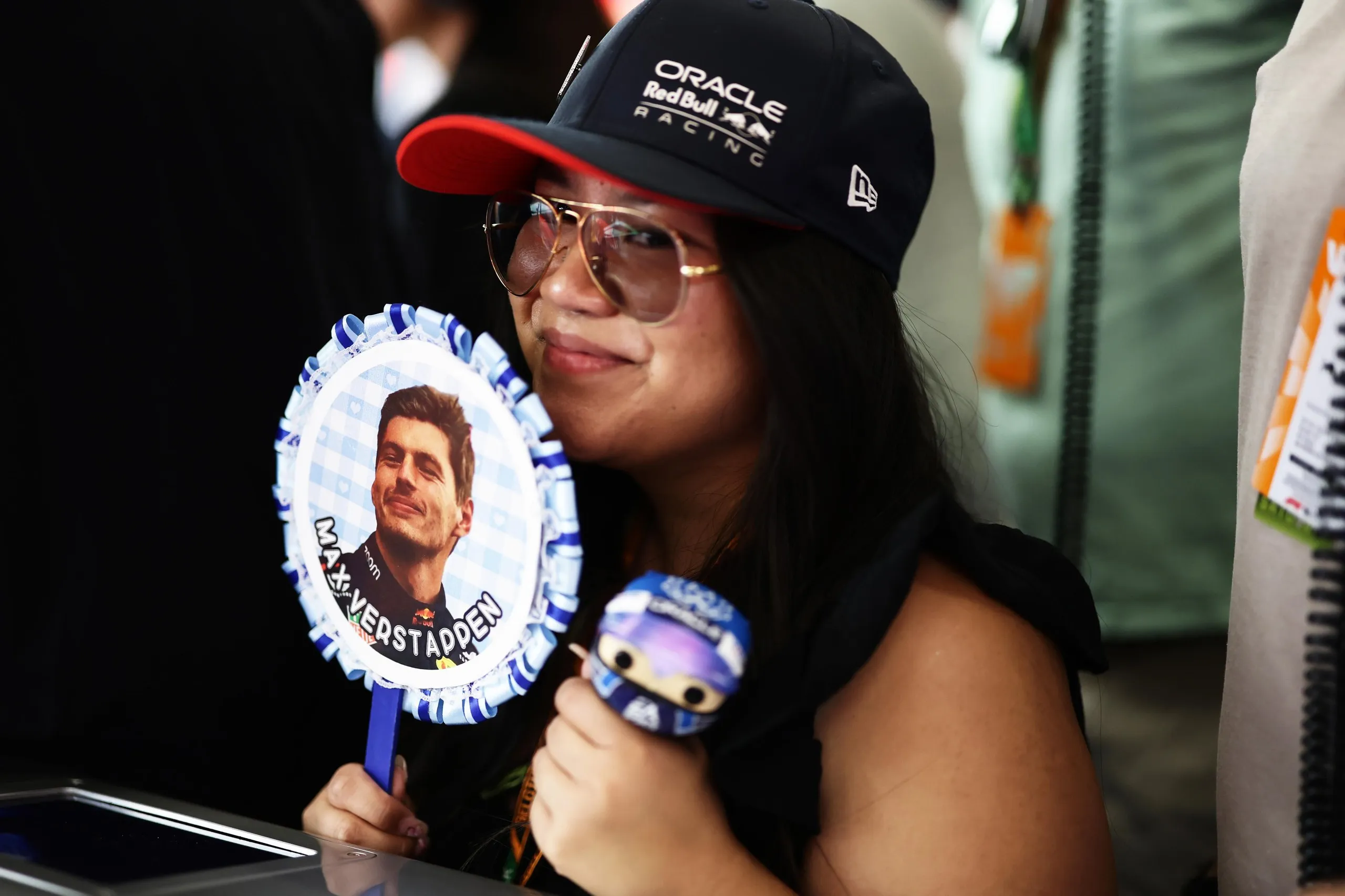 A woman holding a Max Verstappen fan.
