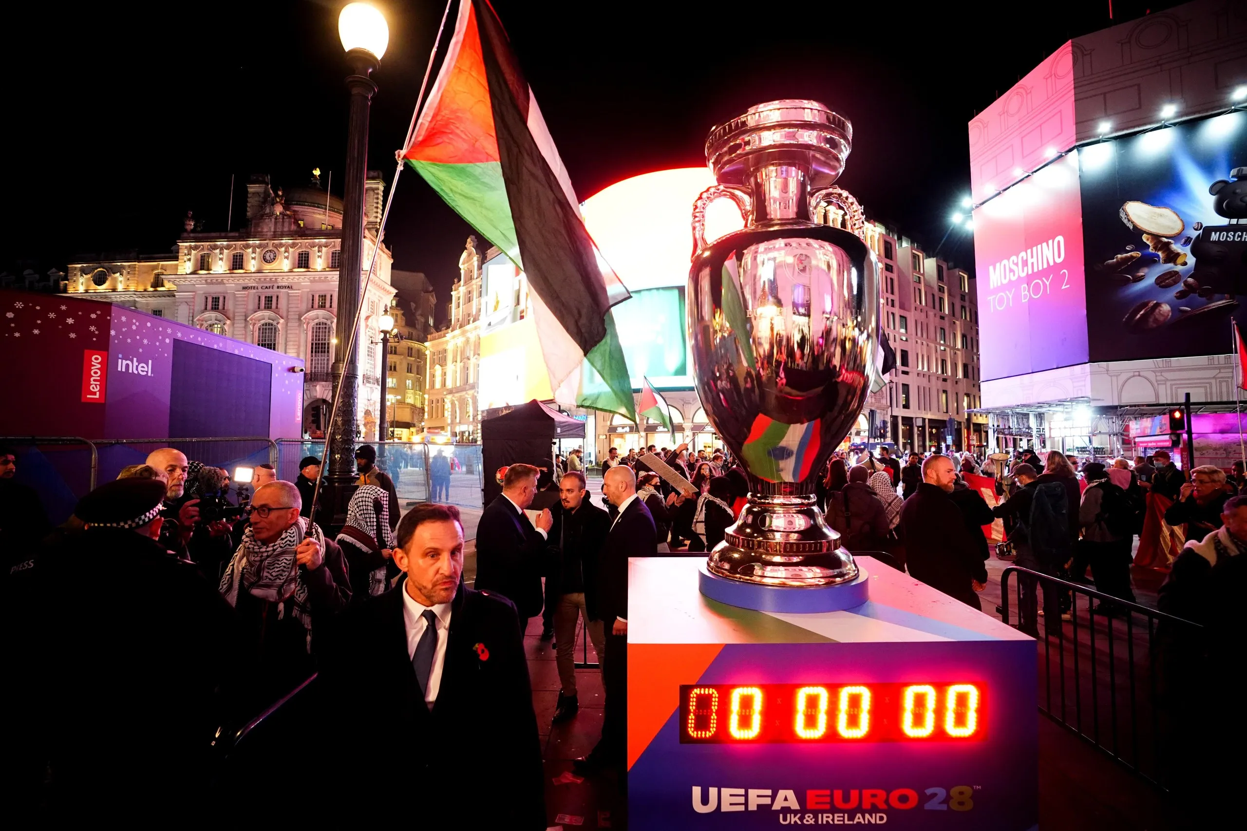 A protester speaking with a police officer near a replica European Championship trophy at the tournament’s official launch
