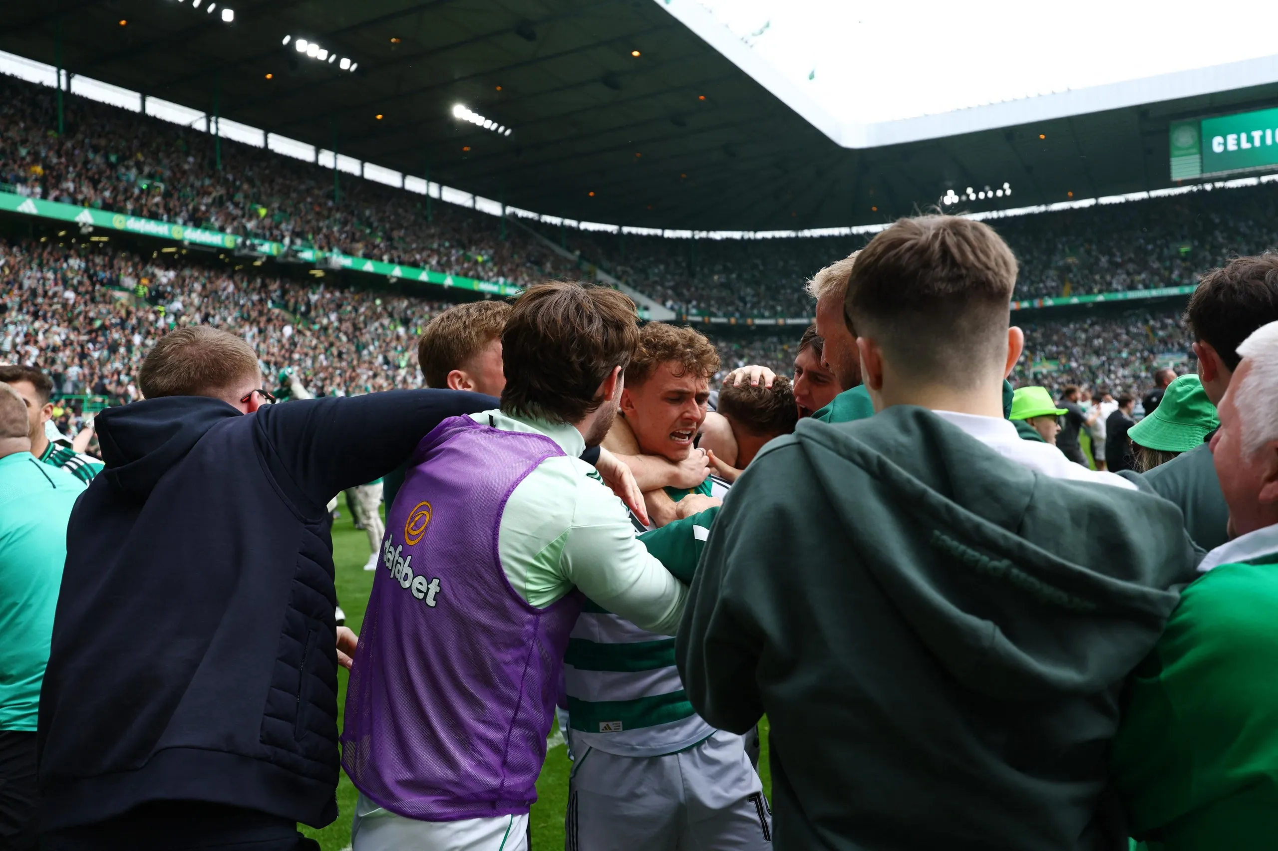 Celtic's Callum Osmand celebrates scoring their third goal with Kasper Schmeichel, Anthony Ralston and fans who have invaded the pitch.