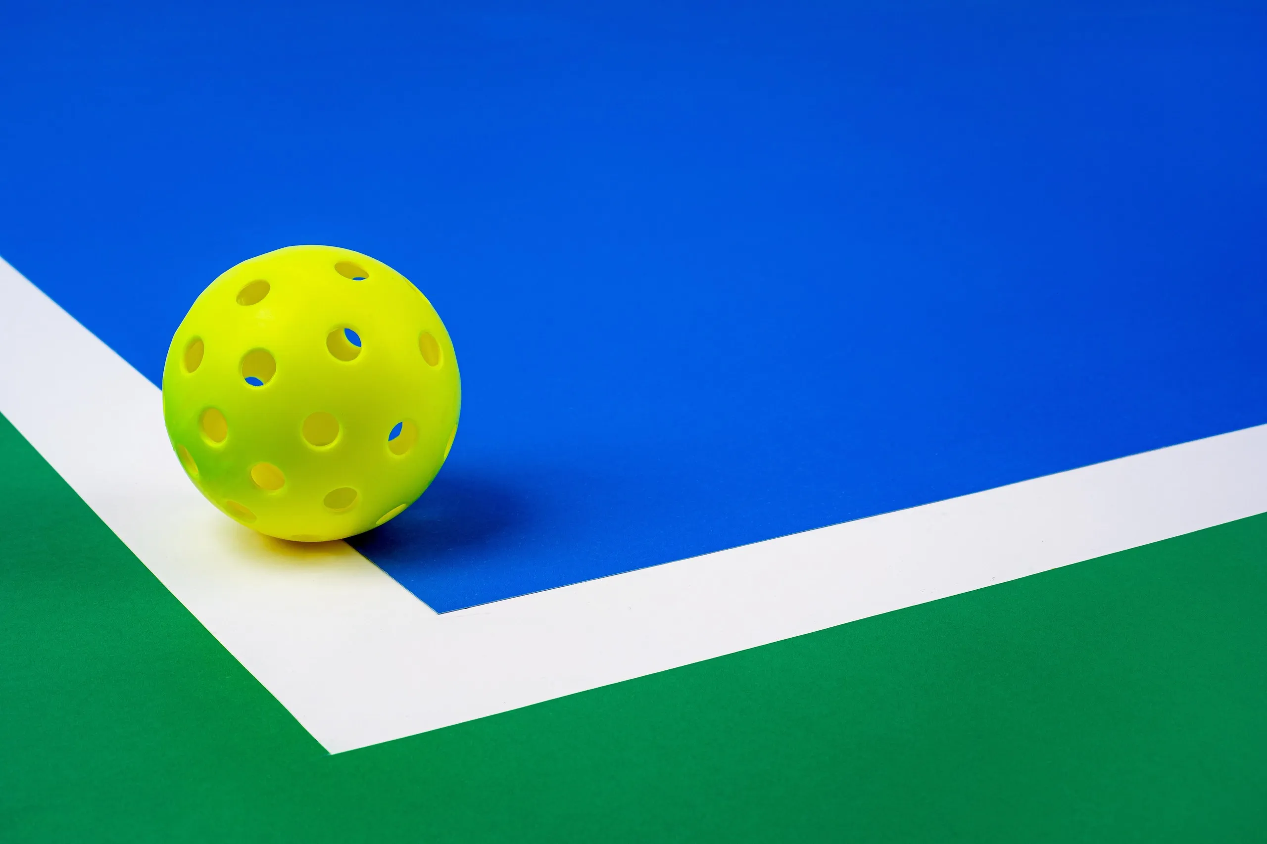 A yellow pickleball on a pickleball court