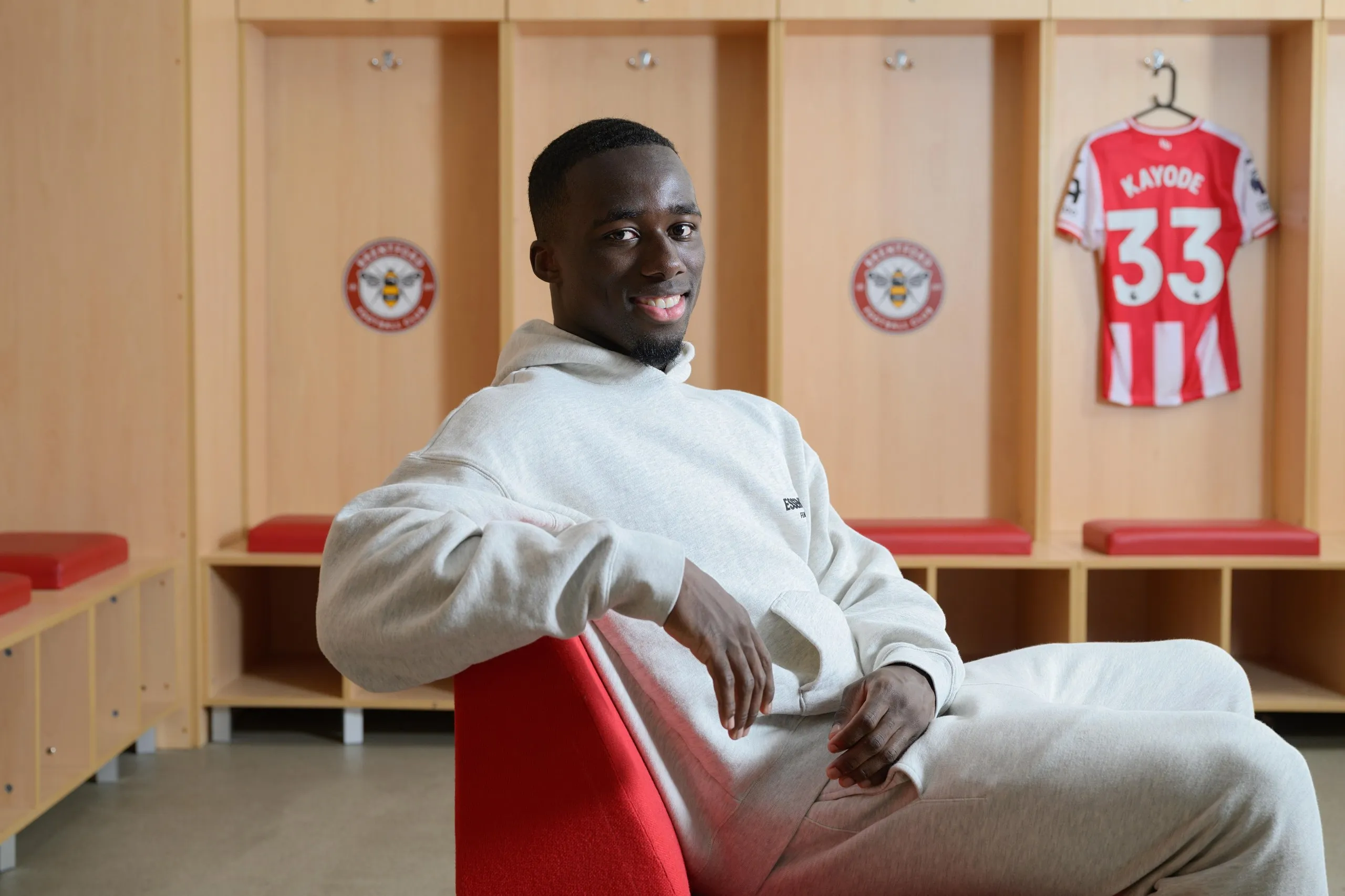 Michael Kayode poses with a Brentford shirt in the background.