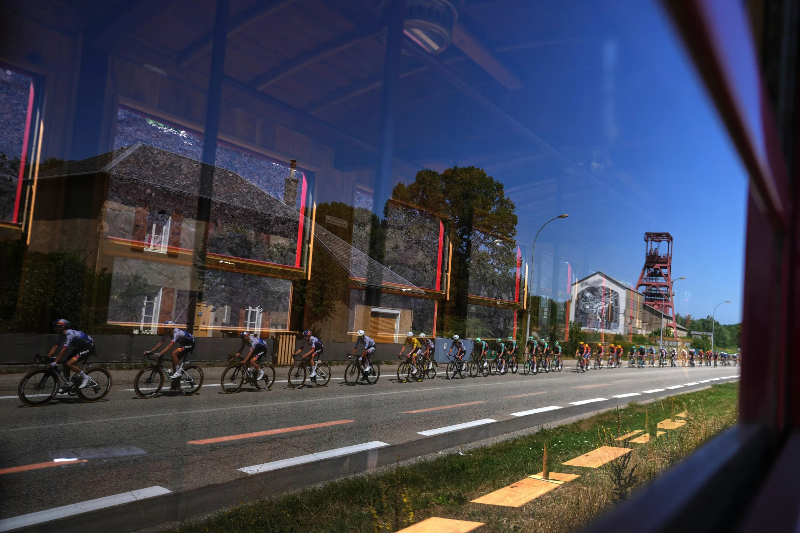 Tour de France riders are reflected in a window 
