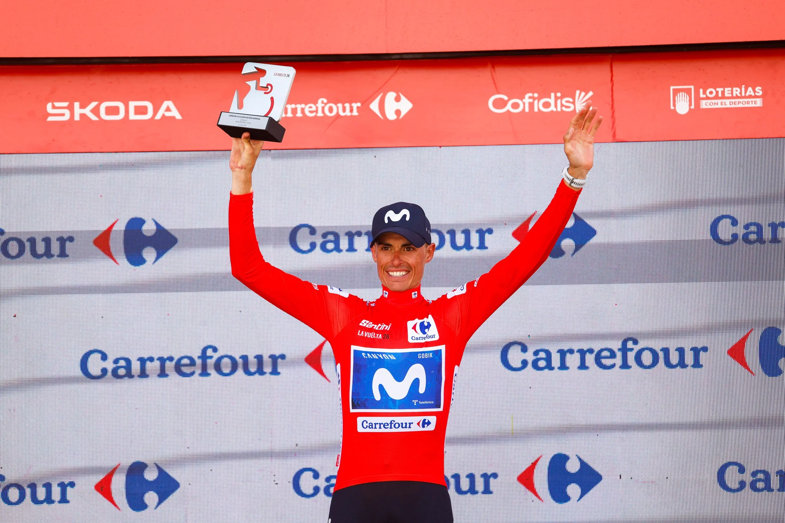 The Spanish Movistar cyclist Enric Mas celebrates on the podium wearing the red overall leader’s jersey following stage 13.