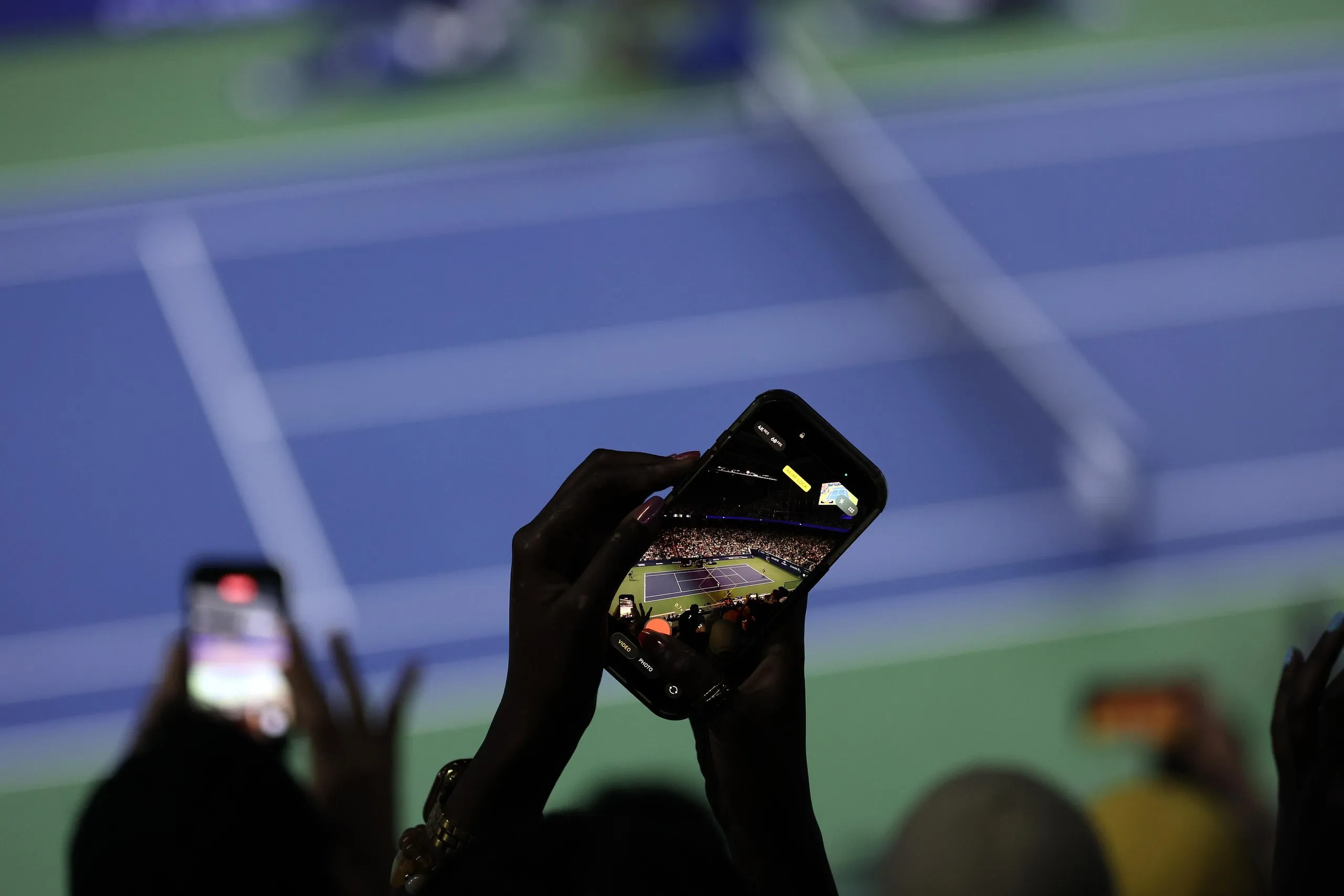 A fan takes a photo of the court during a night session at the US Open